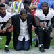 Ray Lewis (center) kneels between two Baltimore Ravens players during the playing of the national anthem before a game. (Matt Dunham/AP Images)